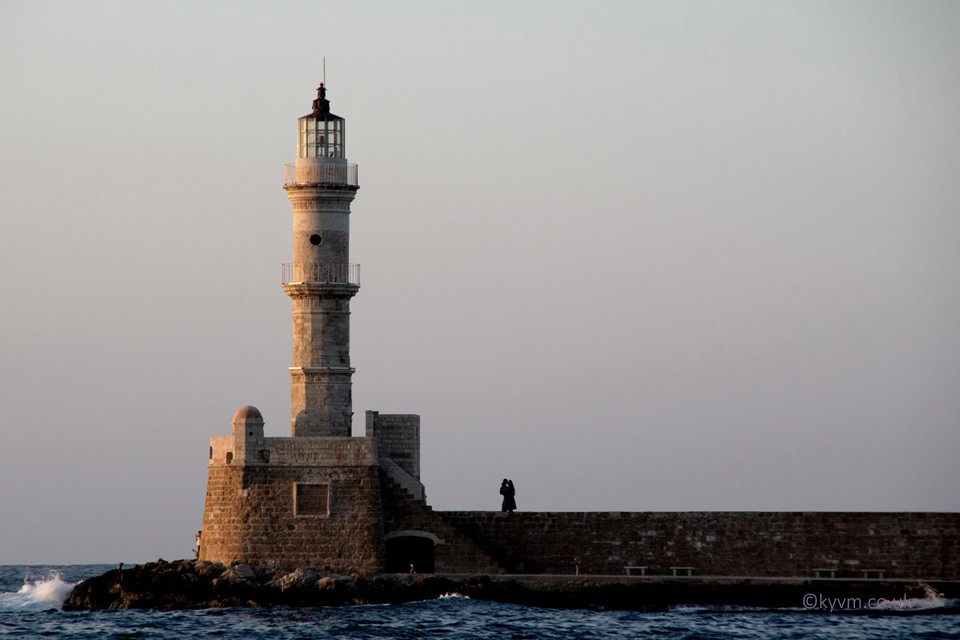 As evening draws in in the city of Chania, romance starts to permeate through the air.  A couple stopped for a moment perfectly silhouetted against the dusk sky as the waves lapped the harbour and lighthouse.